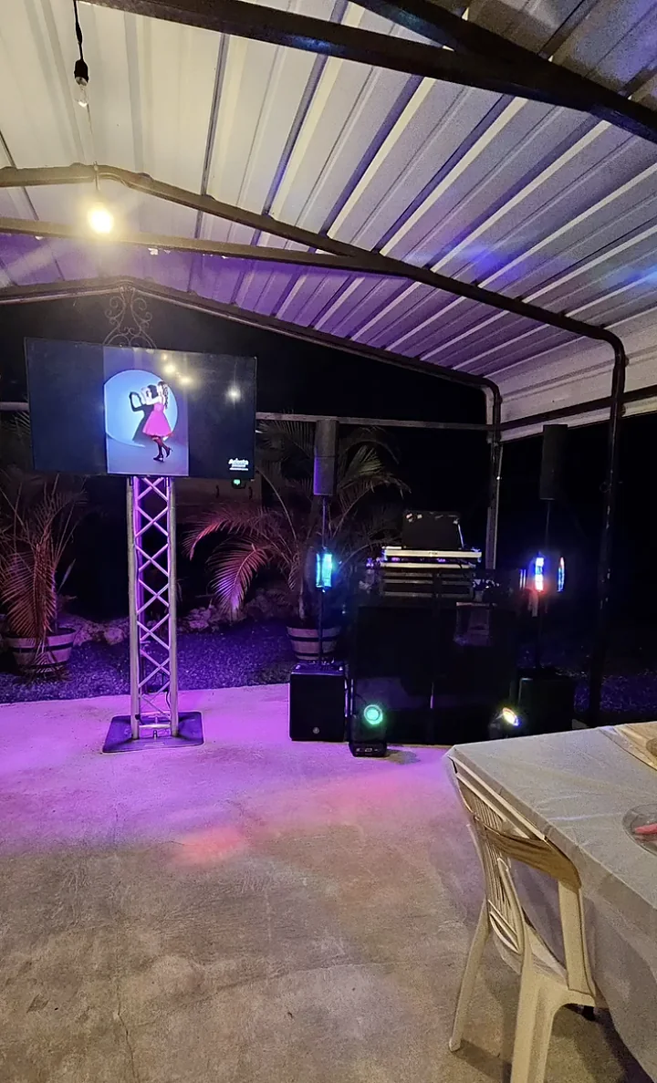 Montaje nocturno en patio residencial con torre de truss, pantalla, bocinas y uplighting morado